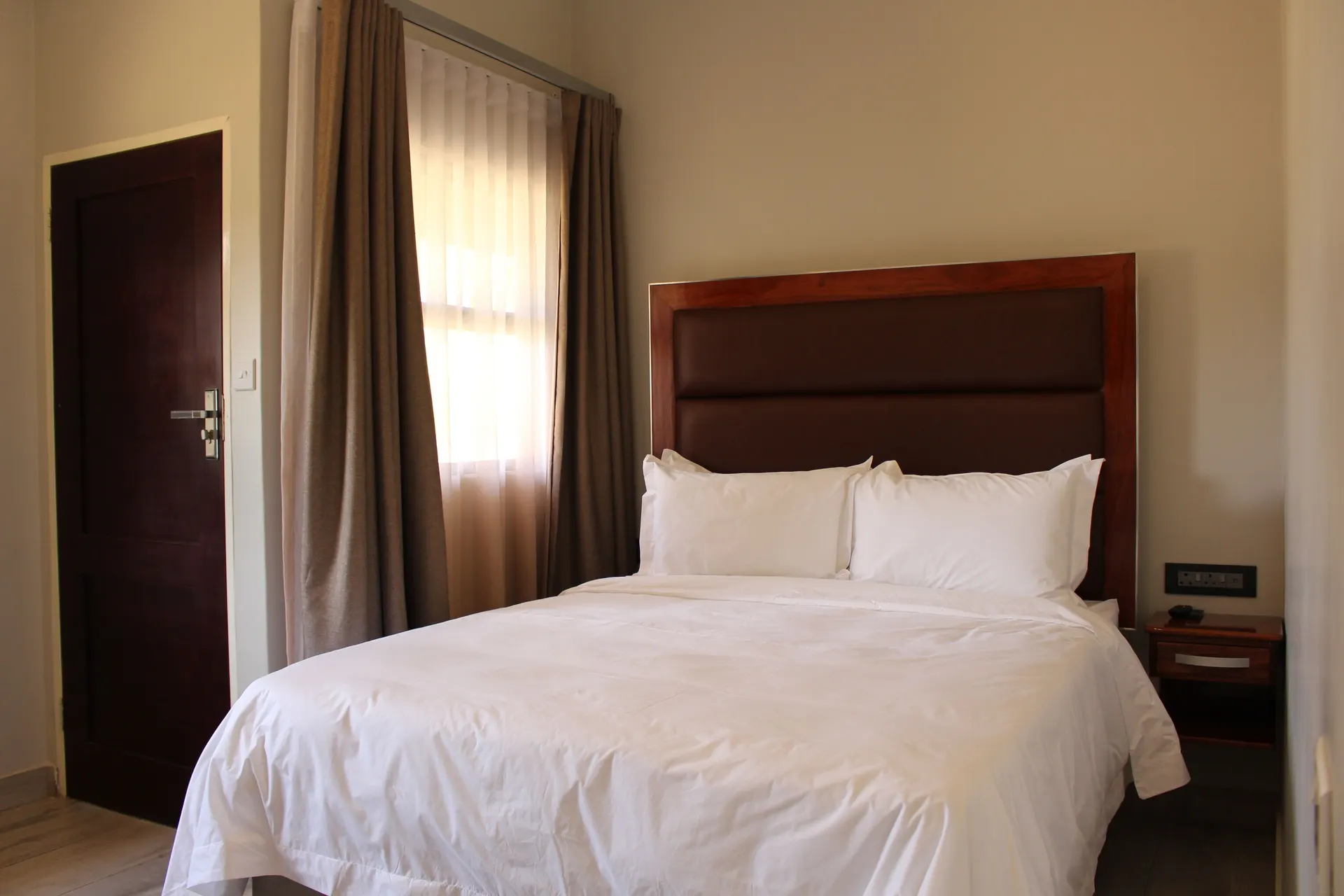 Basic Room at FIRN Lodge with a double bed, leather headboard and a sheer-curtained window in daylight