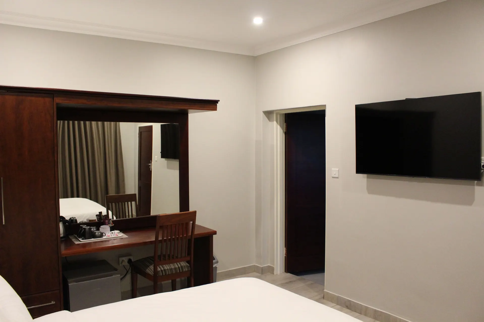 Writing desk, wall-mounted TV and en-suite door in the Deluxe Room at FIRN Lodge