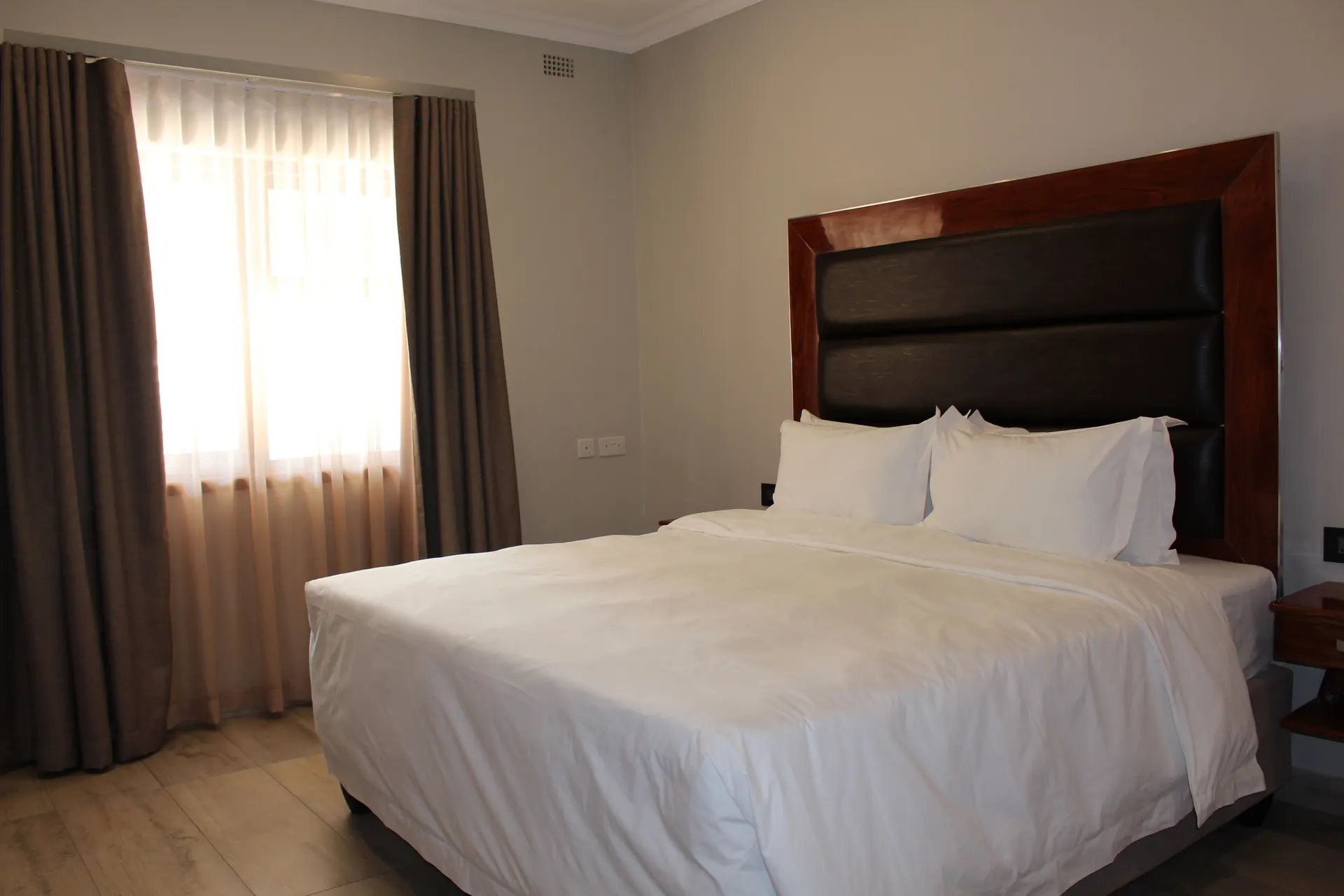 Executive Room at FIRN Lodge with a king bed, black leather headboard and sheer-curtained window