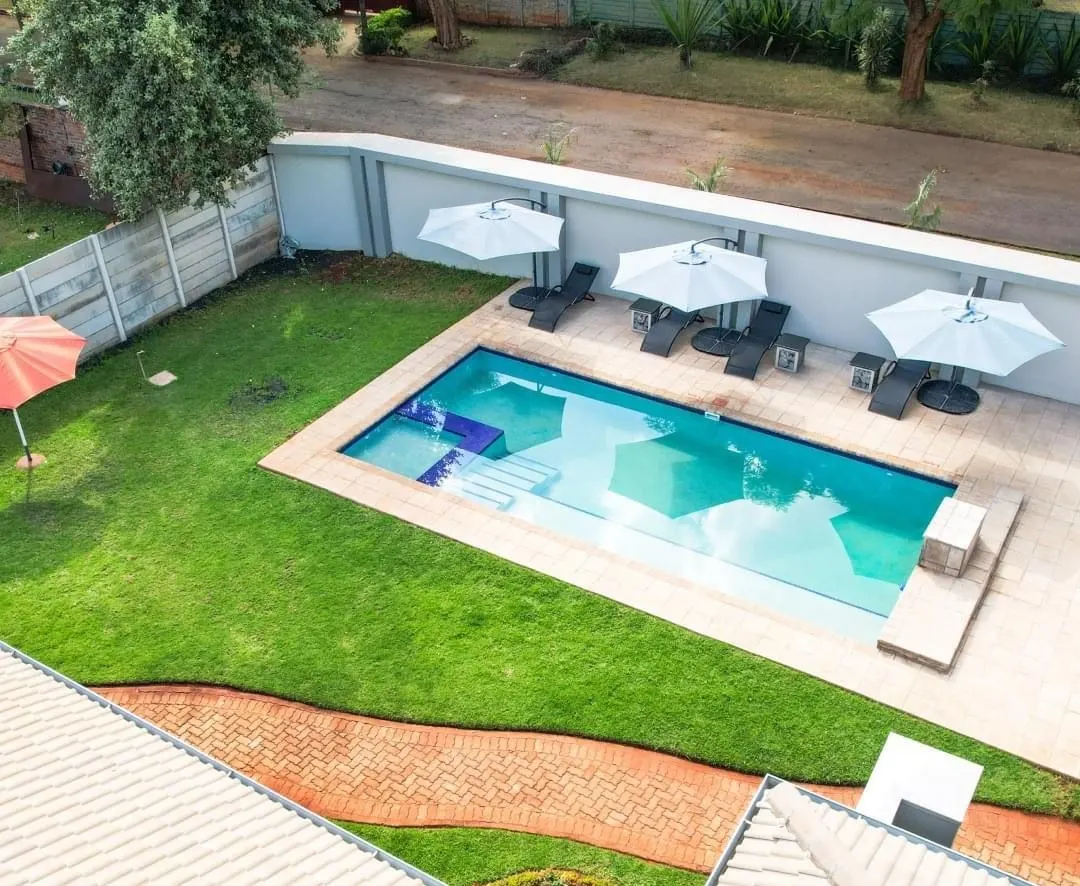 Looking down over the roofs of FIRN Lodge to the pool, umbrellas and lawn