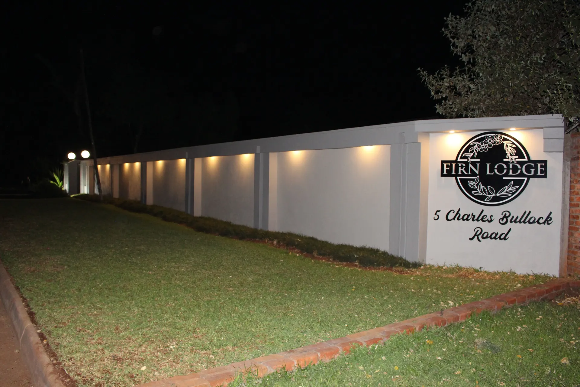 The FIRN Lodge sign and house number on the boundary wall, lit at night
