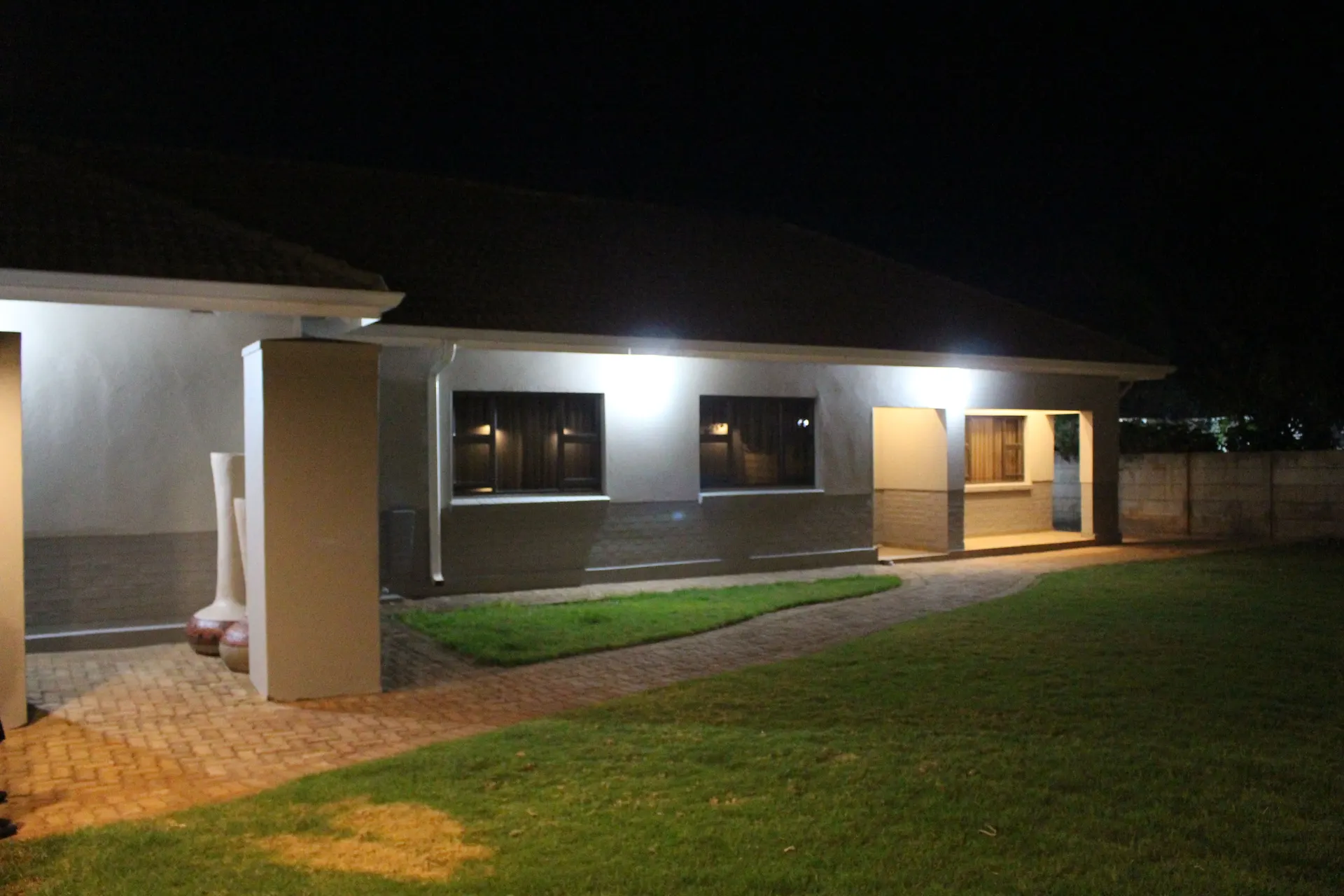 A guest wing at FIRN Lodge at night, its veranda and windows lit beside the lawn