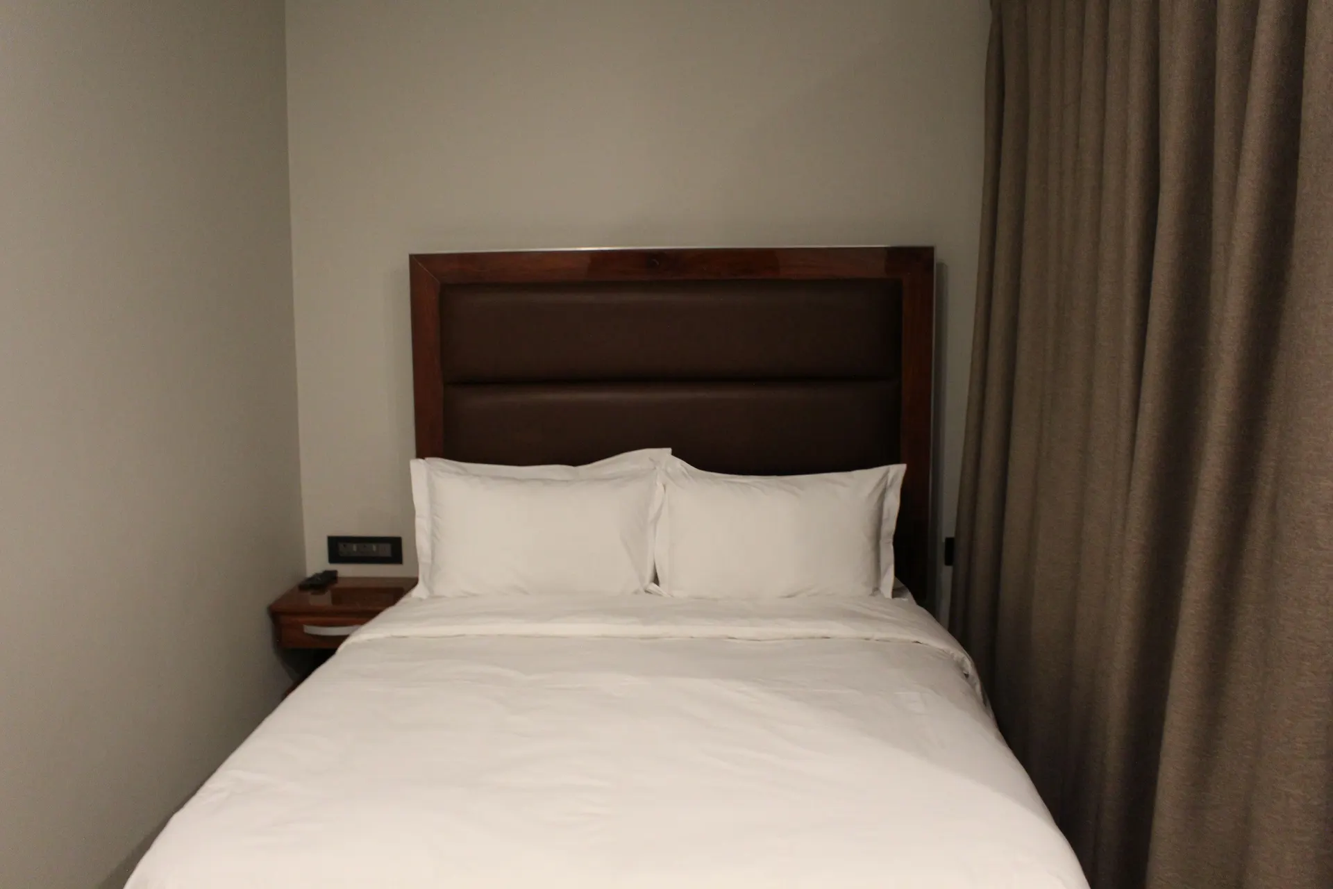 Poolside Deluxe Room at FIRN Lodge with a leather headboard, crisp white linen and full-length curtains
