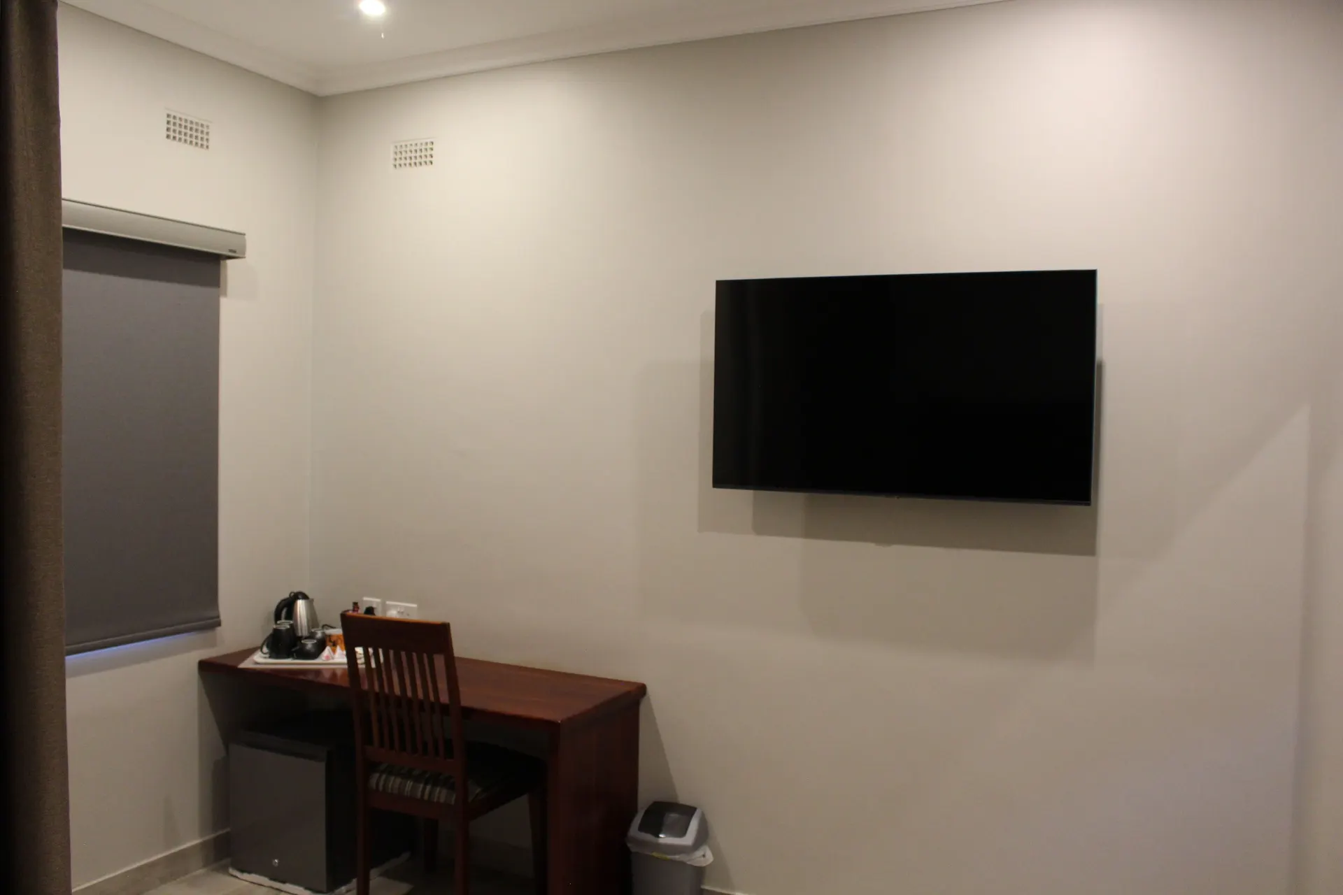 Desk with tea and coffee tray, mini fridge and wall-mounted TV in the Poolside Deluxe Room at FIRN Lodge